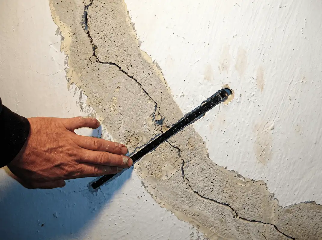 A wall with a large crack is being inspected by a professional in Tacoma, WA